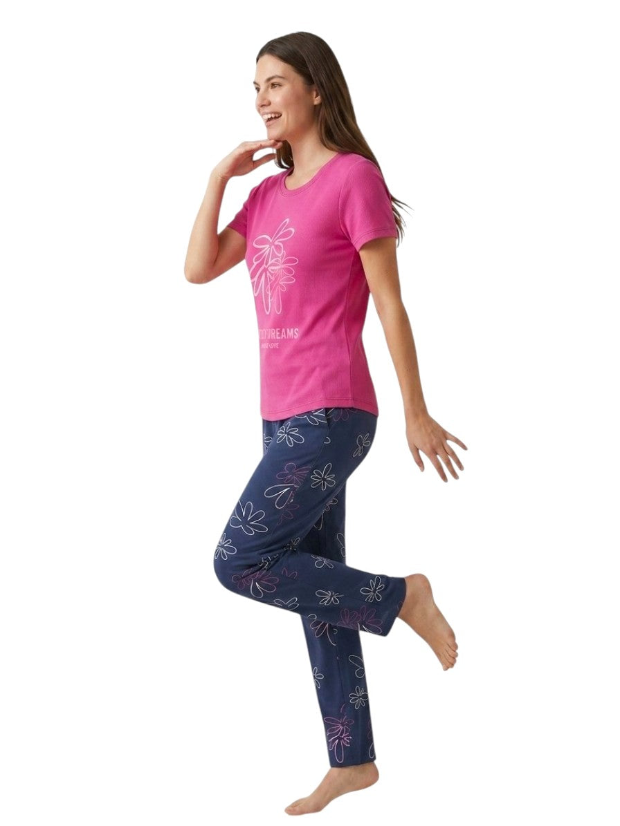 A woman modeling a two-piece pajama set consisting of a hot pink short-sleeve t-shirt with a white floral graphic and navy blue pants featuring a white and pink floral pattern.