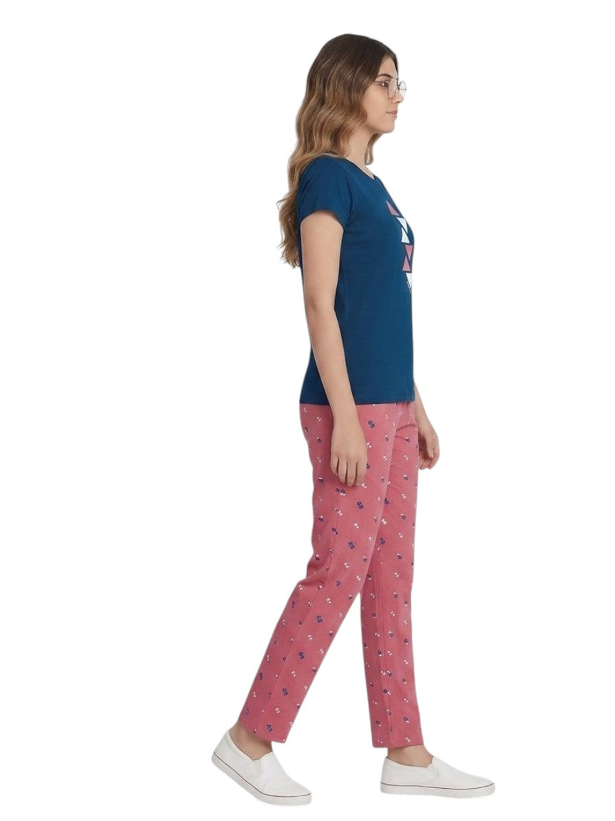A woman modeling a two-piece pajama set consisting of a navy blue t-shirt with a geometric triangle pattern on the chest and coral patterned pants, shot against a plain white background.
