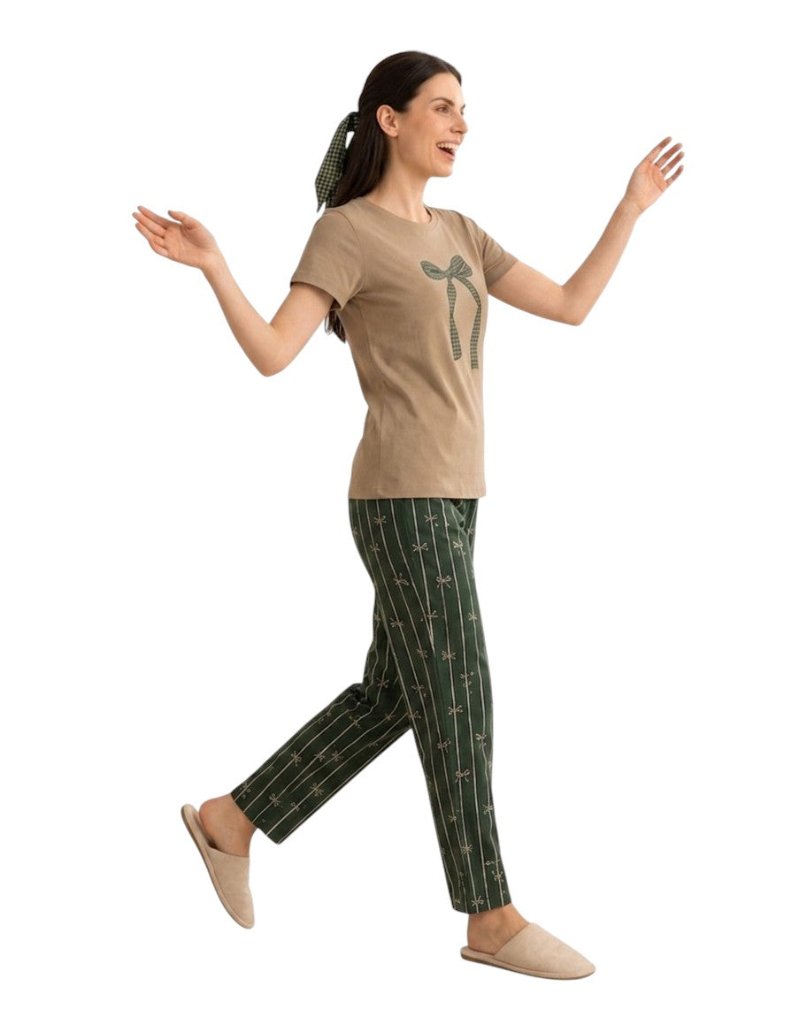 A woman modeling a two-piece pajama set consisting of a moss green short-sleeve t-shirt with a bottle green bow graphic and bottle green pants with vertical white stripes, against a plain white background.