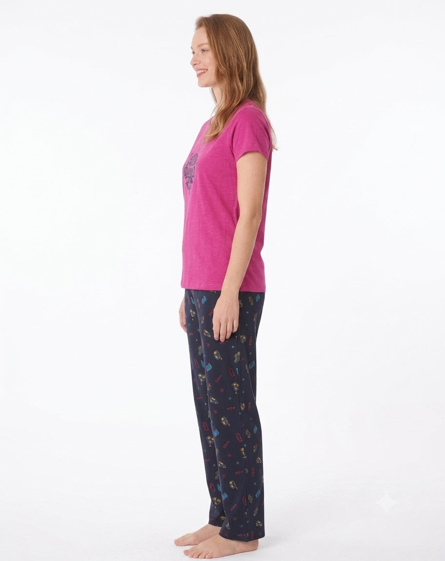 A woman modeling a two-piece pajama set consisting of a toffee pink short-sleeve t-shirt with a dark blue circular graphic and matching navy pants with a colorful pattern, set against a plain white background.